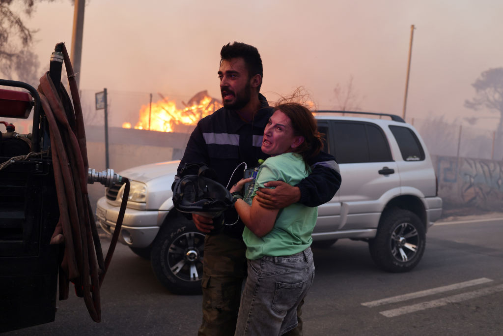 ATHENS, GREECE - AUGUST 11: A woman reacts after her rescue, as a wildfire burns at the village of Varnava, north of Athens, Greece, on August 11, 2024. (Photo by Costas Baltas/Anadolu via Getty Images)