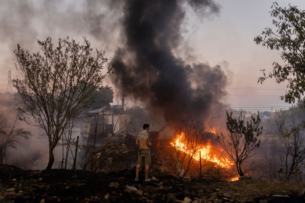 12 August 2024, Greece, Athen: A man looks at a forest fire in Ano Patima near Penteli in the northern Athens region. Just a few kilometers northeast of the Greek capital, firefighters are battling countless fires over an area of around 200 square kilometers. The government has now asked the EU for support. Photo: Socrates Baltagiannis/ (Photo by Socrates Baltagiannis/picture alliance via Getty Images)